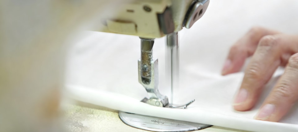 Operator guiding fabric through an industrial sewing machine