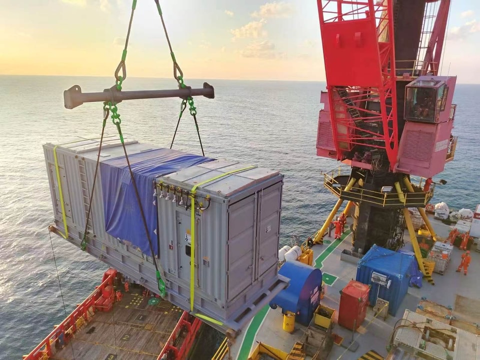 Crane lifting a containerized generator for offshore deployment